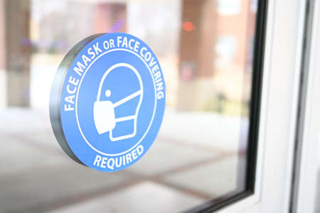 Mask mandate sign on a store door. Face mask or face covering are required in public places. Pandemic restrictionsの写真素材