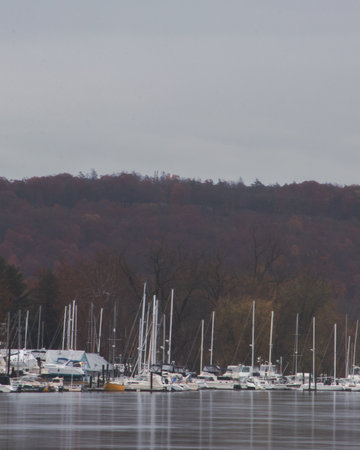 Collection of boats sitting in in front of a marina. Mountain in the background and cloudy sky at the top of the frame.の写真素材