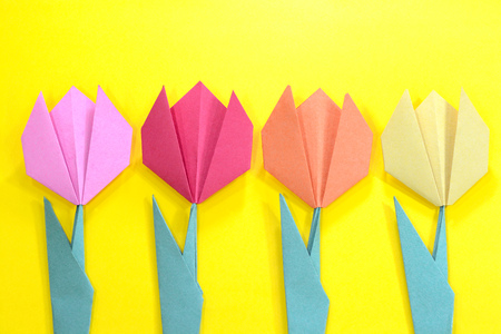 Origami bright colored tulip flowers on a yellow background.の写真素材