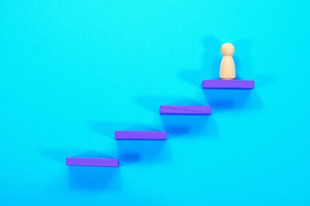Leadership concept. Wooden figurine climbing and reaching the top stepの写真素材