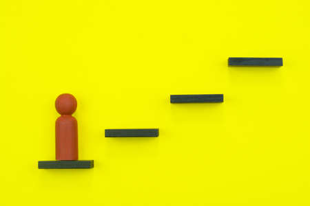 Leadership and career concept. Wooden figurine climbing up the stepsの写真素材
