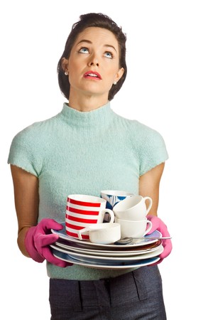Portrait of a young beautiful housewife holding a pile of dirty dishes and looking fed up. Isolated over white.の写真素材