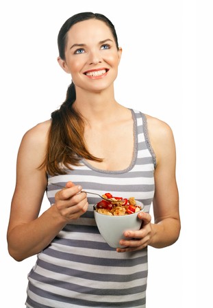 Portrait of a beautiful young woman smiling and holding a healthy bowl of cereal with strawberries. Isolated over white. の写真素材