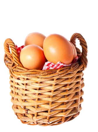 Fresh delicious brown free range chicken eggs in a cane basket with a red checkered clothの写真素材