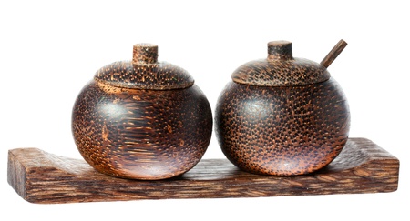 A pair of wooden old fasioned asian style salt and pepper bowls with lids and spoon. Isolated over white with clipping path.の写真素材