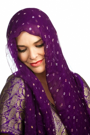 A beautiful young Indian or asian woman wearing a head scarf looking down smiling. Isolated over whiteの写真素材