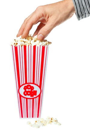 A hand grabbing delicious popcorn out of a container. Isolated over white.の写真素材