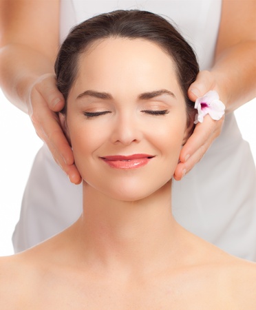 A portrait of a beautiful young woman getting a face massageの写真素材