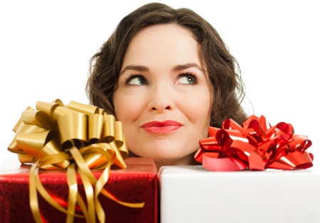 Beautiful young woman peeking over beautifully wrapped Christmas gifts and looking at copyspaceの写真素材