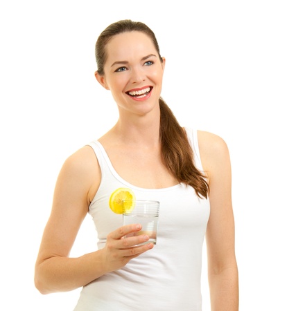 Isolated portrait of a young beautiful laughing woman holding a glass of water with slice of lemon.の写真素材