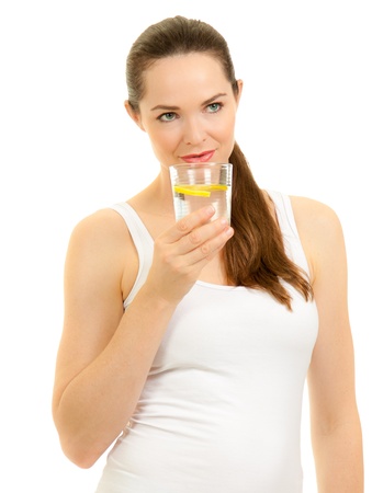 Isolated portrait of a young beautiful fresh woman drinking a glass of water with slice of lemon.の写真素材