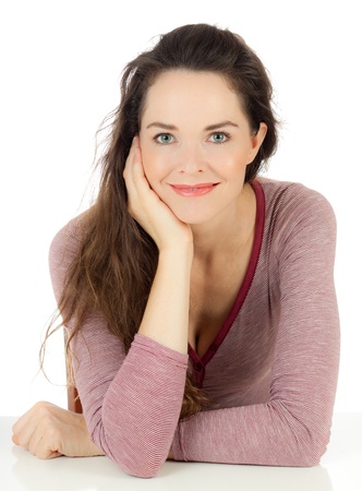 Isolated portrait of a relaxed lovely young woman sitting at a tableの写真素材