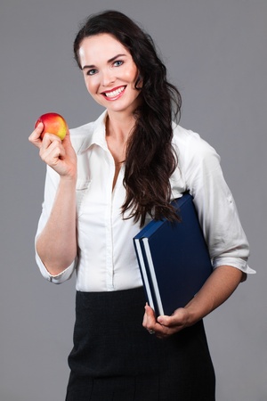 Portrait of a confident attractive business woman holding book and an appleの写真素材