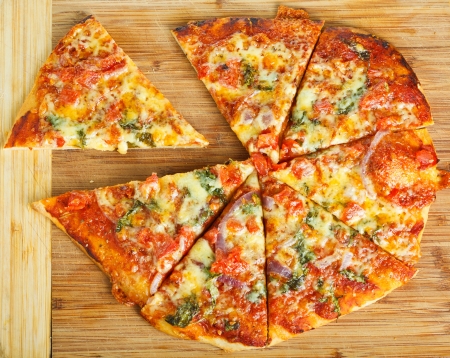A delicious homemade pizza on a wooden chopping board の写真素材