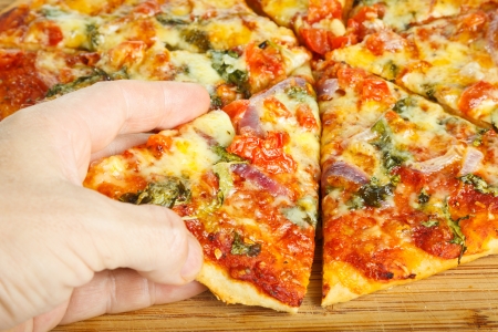 Close-up of a hand taking a slize of homemade pizzaの写真素材