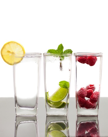 Three colorful alcoholic drinks with various berries, fruit and ice  On a table with reflection and isolated over white の写真素材