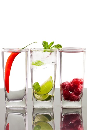 Three glasses with alcoholic drinks with fruits and berries  On a table with refelction and isolated over white の写真素材