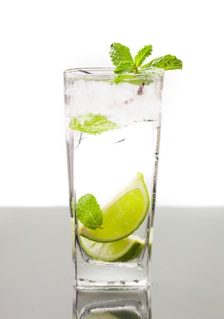 A cold alcoholic drink, mojito, with lime, mint soda and ice  On table with refelction and isolated over whiteの写真素材