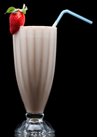 A delicious cold fruit smoothie or milk shake decorated with strawberry. Isolated on blackの写真素材
