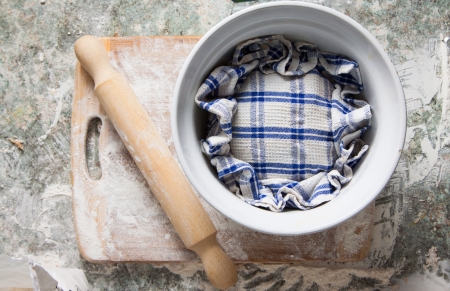 A homebaked dough is rising under a kitchen towelの写真素材