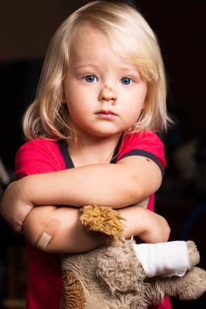 An injured cute little boy with band aid on his elbow, holding a puppy  の写真素材