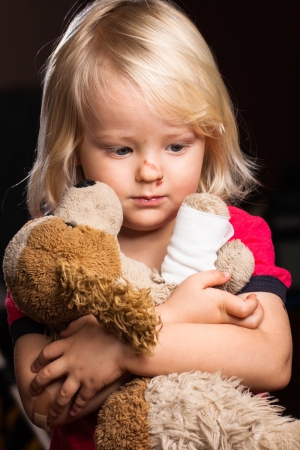 A cute injured little boy looking sad holding his stuffed dog toy  の写真素材