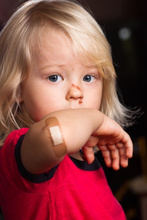 A young injured boy showing his elbow with  band aid on の写真素材