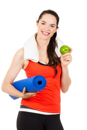 A fit, healthy happy beautiful woman holds an apple and yoga mat  Isolated on white の写真素材