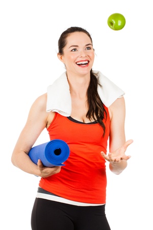 A fit, healthy happy beautiful woman throws an apple in the air and laughs  Isolated on white の写真素材