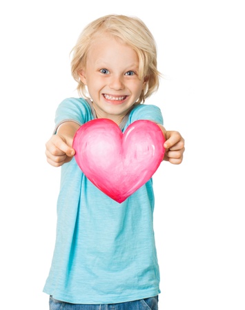 A very cute young blond boy smiling and holding out a love heart  Isolated on white の写真素材