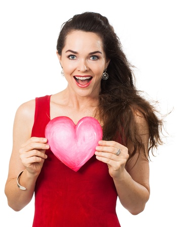 A beautiful happy woman looking surprised and holding a red love heart  Isolated on white の写真素材