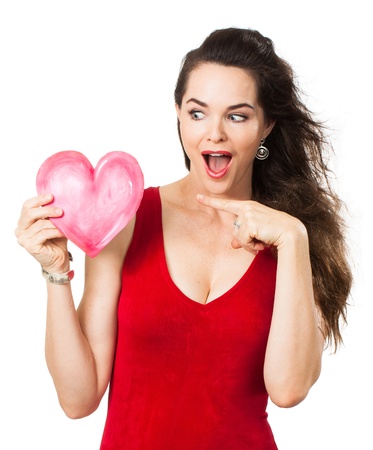 A beautiful excited surprised woman holding and pointing ata love heart  Isolated on white の写真素材