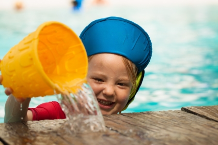 A cute little boy playing and puring water out of a bucket の写真素材