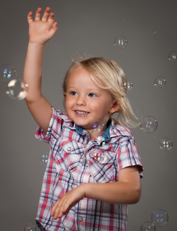 A very happy cute little boy catching soap bubbles の写真素材