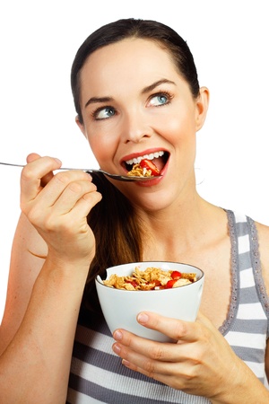 Healthy beautiful woman eating a nice bowl of cereal and strawberries for breakfast  Isolated on white の写真素材