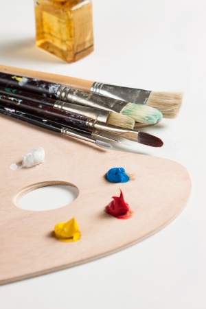Paint brushes, tubes of oil paint and dollops of paint on a blank canvasの写真素材