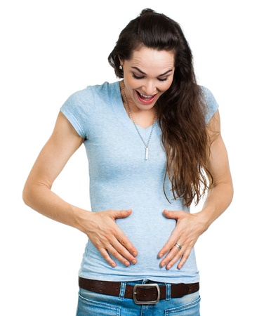 A happy newly pregnant woman smiling and looking and holding tummy  Isolated on white の写真素材