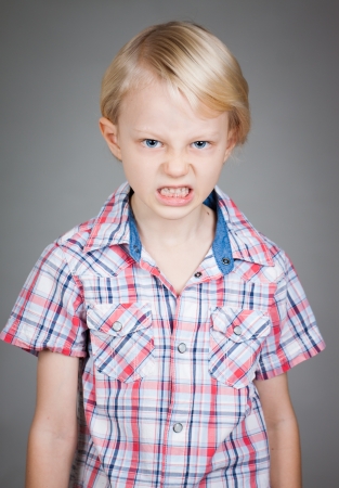 A frustrated and angry looking young boy  pulling a face. Isolated on white.の写真素材