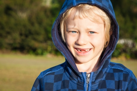 A close-up portrait of a cute happy smiling boy with missing front teeth.の写真素材