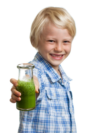 A happy smiling boy holding out a bottle of green smoothie or juice  Focus on smoothie  Isolated on white の写真素材