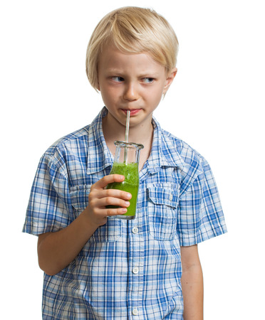 A cute boy, looking suspicious while drinking a green smoothie  Isolated on white の写真素材