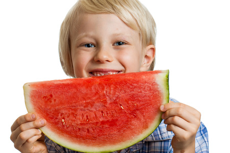 Close-up shot of a cute happy  boy smiling behind a juicy  slice of watermelon. Isolated on white.の写真素材