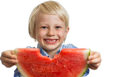 A close-up shot of a smiling cute boy holding out a nibbled water melon. Isolated on white.の写真素材
