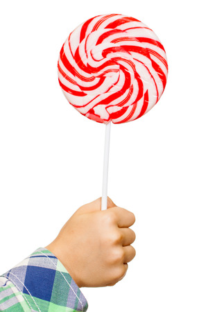 A childs hand is holding a big white and red lollipop. Isolated on white.の写真素材
