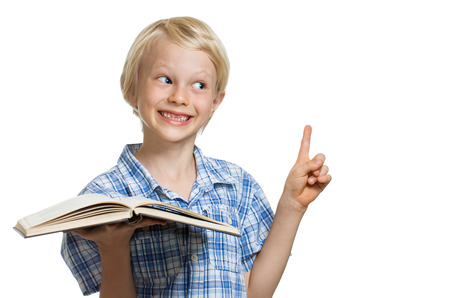 A cute smiling young boy holding a book and pointing to copy-space. Isolated on white.の写真素材