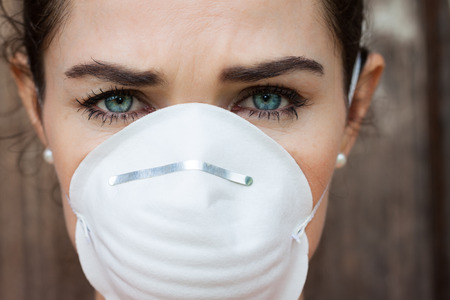 Close-up of an unhappy woman wearing a face mask to deal with virus or pollution.の写真素材
