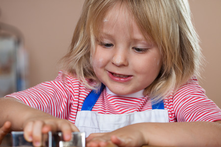 A close-up of cute young boy baking and cutting out a gingerbread star cookieの写真素材
