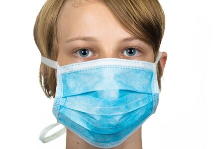 Young teenage boy wearing a protective mask to protect against virus infection.  Isolated on white.の写真素材