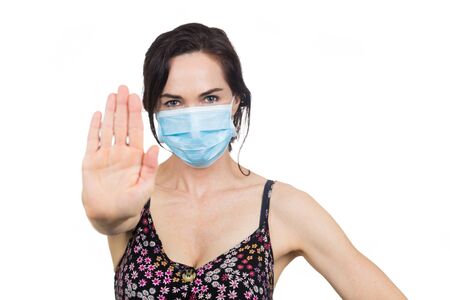 Woman wearing protective face mask making a stop sign with hand.. Isolated on white.の写真素材