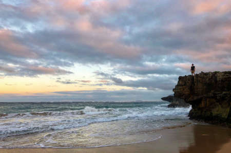 Man stands cliffside over Hawaiian oceanの写真素材